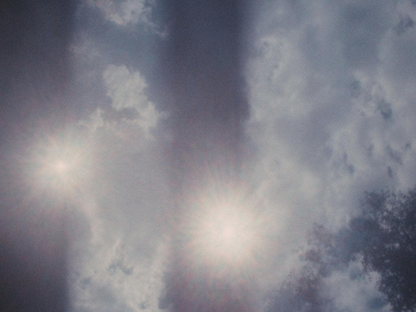Clouds appear in three vertical bands, lens flares appear in two