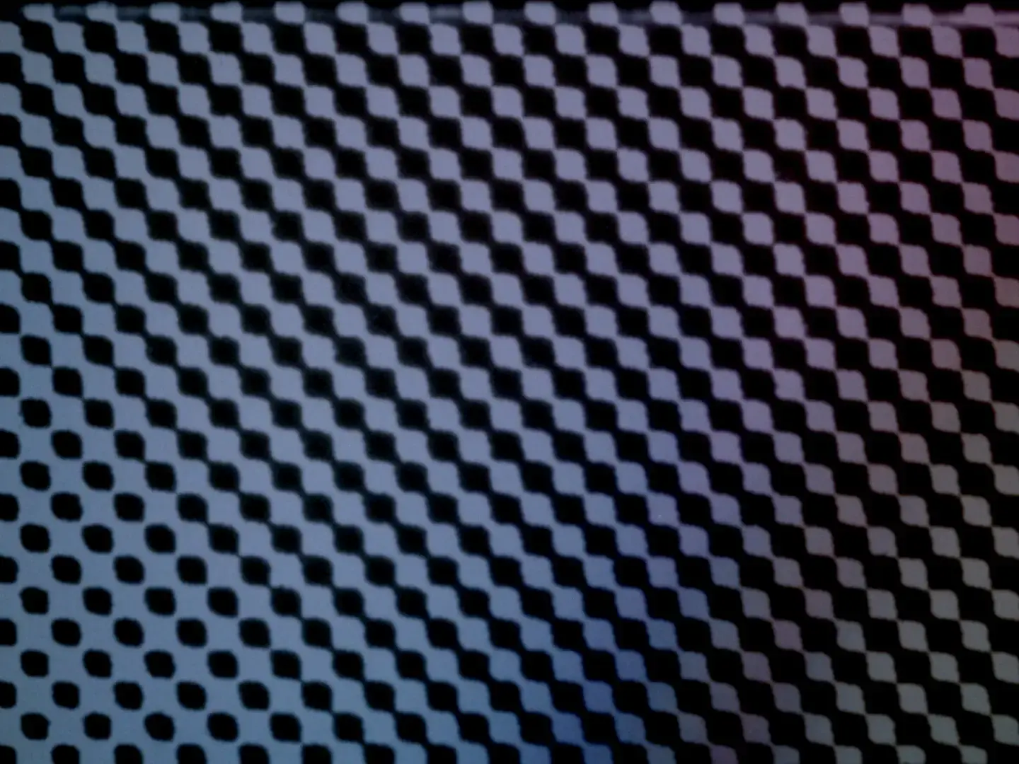 Diagonal grid of dark halftone dots on contact-printed film with subtle blue and magenta color gradients across the frame