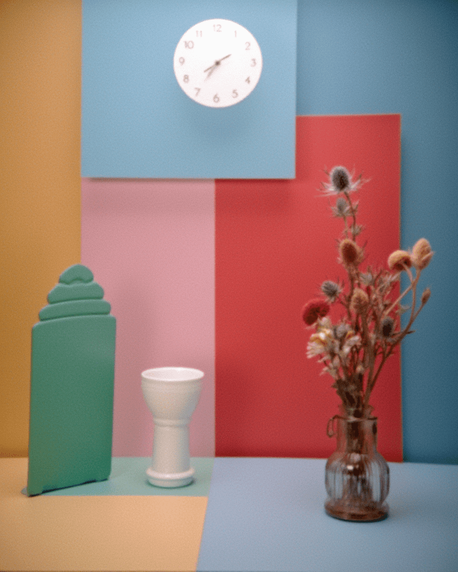 AI-generated still life with wall clock, white ceramic vase, dried flowers, and geometric color panels in teal, coral, pink, and mustard