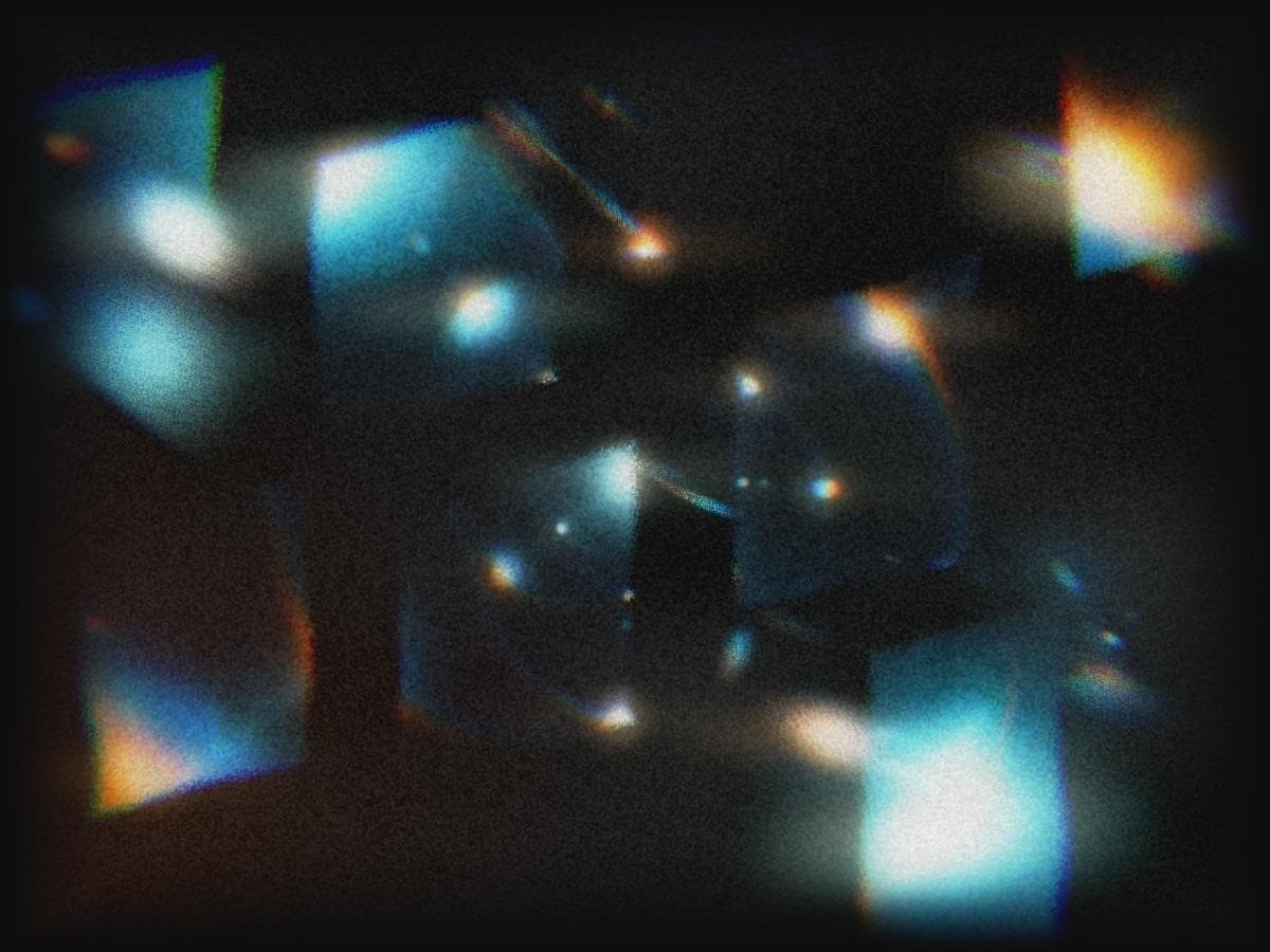 Blurred blue panels with orange prismatic edges and soft points of light on black