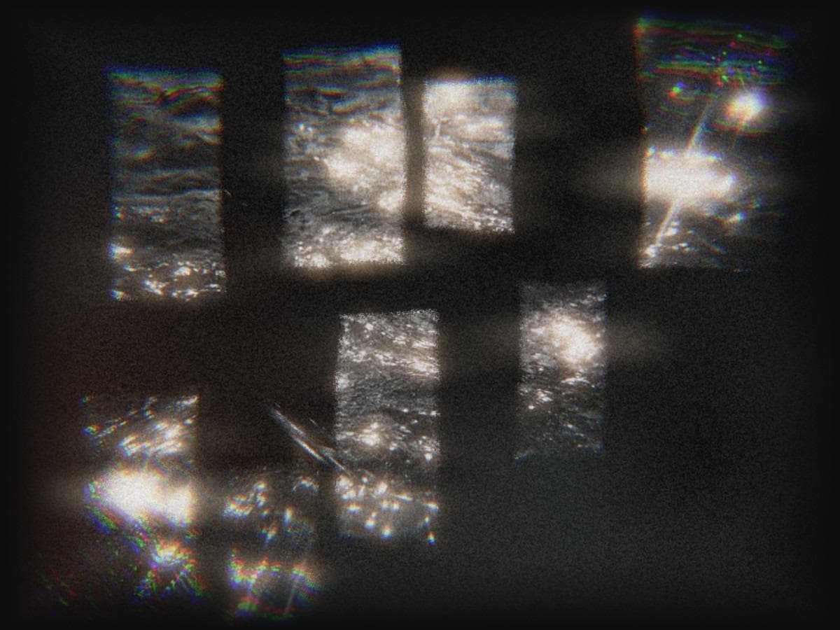 Rectangular panels of sunlight glittering on water, floating in a dark grainy field